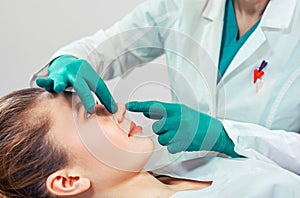 Rhinoplasty, the surgeon hands touches the patient s nose. People, cosmetology, plastic surgery and beauty concept - photo