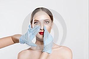 Rhinoplasty. wish to be beautiful need for beauty. Closeup portrait doctor hands with gloves  touching woman face nose want to