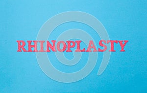 Rhinoplasty word in red letters on a blue background. The concept of the modern procedure for changing the correction