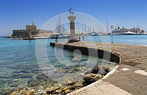 Rhodes Mandraki harbor with castle and symbolic deer statues, Greece