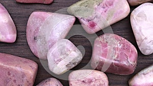 Rhodochrosite heap up jewel stones texture on brown varnished wood background. Moving right seamless loop backdrop