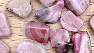 Rhodochrosite heap up jewel stones texture on light varnished wood background. Moving right seamless loop backdrop