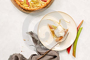 Rhubarb open faced round pie cut and served on a plate with ice cream, overhead view