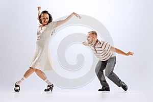 Rhythm and expression. Energetic dance couple in retro style outfits dancing lindy hop, jive  on white