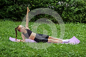 Rhythmic gymnastics. Child does outdoor sports exercises using fitness mat. Girl is doing gymnastics