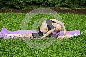 Rhythmic gymnastics. Child does outdoor sports exercises using fitness mat. Girl is doing gymnastics