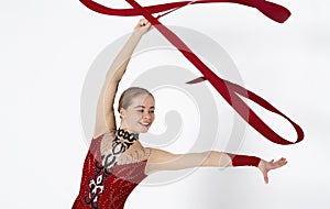 Rhythmic gymnastics exercises. Young slender woman practicing with red ribbon on white background