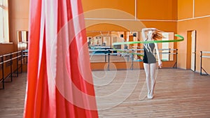 Rhythmic gymnastics - young woman training a gymnastics exercise with a green ribbon