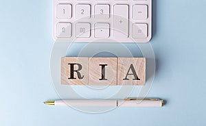 RIA on wooden cubes with pen and calculator, financial concept