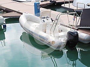 Rib boat moored in turquoise sea water near a wooden pier