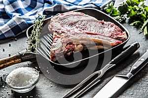 Rib eye steak in grill pan with herbs salt pepper fork and knife