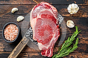 Rib eye steak on a meat cleaver. Raw Marble beef black Angus, ribeye. Dark wooden background. Top view