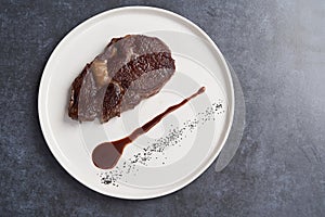 Rib eye steak on white plate, close-up. Sliced tenderloin steak