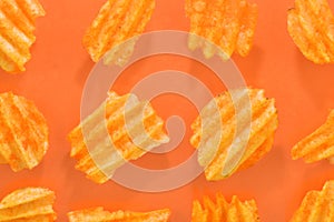 Ribbed potatoes snack with pepper on pastel orange background. Ridged potato chips on orange background. Collection