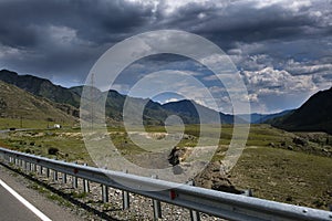 ribbon of the road among the slopes of the mountains on the expanses of Altai on a summer day