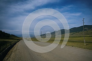 ribbon of the road among the slopes of the mountains on the expanses of Altai on a summer day