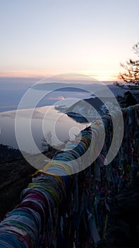 Ribbons for good luck tied on the observation platform of the Chersky stone in Listvyanka. Vertical view. Sunset in Siberia