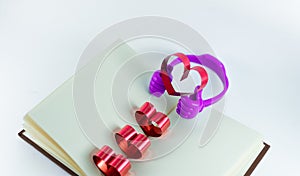 Ribbons shaped as hearts in a book for your text on white background