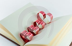 Ribbons shaped as hearts in a book for your text on white background