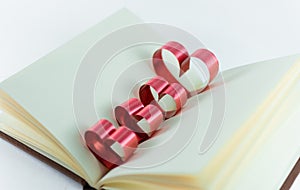 Ribbons shaped as hearts in a book for your text on white background