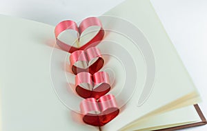 Ribbons shaped as hearts in a book for your text on white background