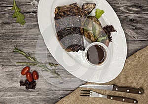 Ribeye steak from marble beef meat with vegetables and barbecue sauce. Served on a plate of black stone with fork and knife .