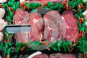 A ribeye steak is presented on a black tray and adorned with food decorations in a butcher shop