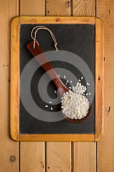 Rice Arborio in a wooden spoon on a chalkboard