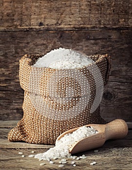 Rice in bag with scoop on wooden background