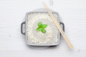 Rice with basil in ceramic bowl with wooden chopsticks
