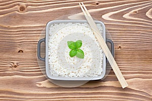 Rice with basil in ceramic bowl with wooden chopsticks