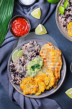 Rice with black beans, fried chicken breast and tostones, plantains photo