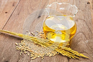 Rice bran oil in bottle glass and unmilled rice on wooden background