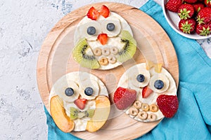 Rice cakes with yoghurt and fresh fruits in a shapes of cute owls on a wooden board, meal for kids idea, top view