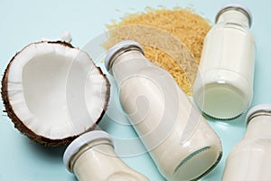 Rice coconut vegan milk in glass bottles on blue background