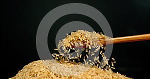 Rice falling in a Wooden Spoon against Black Background