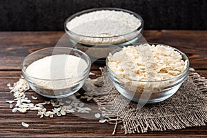 Rice flakes and flour on dark wooden. photo
