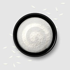 Rice flour in a black bowl with scattered white grains on gray background. Top view