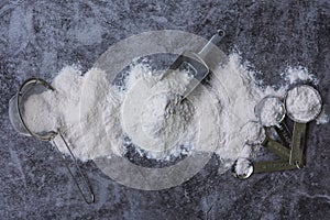 Rice flour Thai organic in a measuring spoon with wooden bowl on a pile of white rice, ear of paddy and strainer on concrete