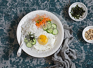 Rice with fried egg, pickled carrots, cucumber and seaweed. Healthy diet food concept.