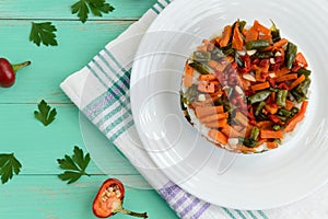 Rice and fried vegetables asparagus beans, carrots - vegan diet garnish. Decorated layers of salad on a white plate.