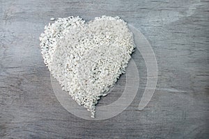 Rice grains formed in heart shape on wooden background