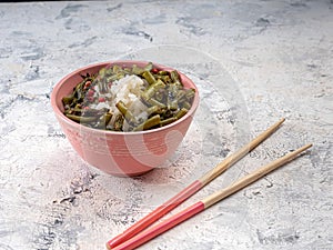 Rice and green beans in a ceramic bowl with wooden chopsticks