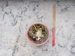 Rice and green beans in a ceramic bowl, wooden sticks on a white background