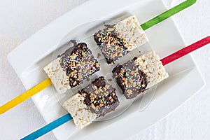 Rice krispie cakes on a stick dipped in chocolate.