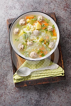 Rice meatball soup with celery, carrots, onions and potatoes close-up in a bowl on. Vertical top view