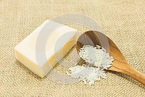 Rice milk beside jasmine rice in wooden spoon on gunny sack pattern