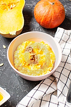 Rice milk pumpkin porridge with walnuts, butter and honey on stone table. Healthy food.