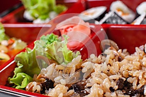 Rice with mushrooms. Fresh food portion in japanese bento box with salad, main course. Sushi roll with vegetables