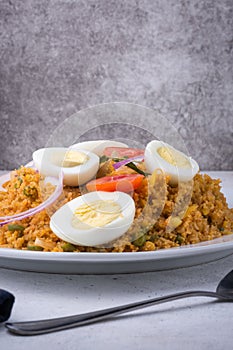 Rice noodle dish or string hoppers biryani with boiled eggs, tomatoes, onions and curry leaves, closeup view